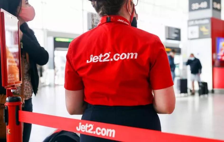 Співробітник розмовляє з пасажиром у святковій зоні реєстрації Jet2 Plc в лондонському аеропорту Станстед